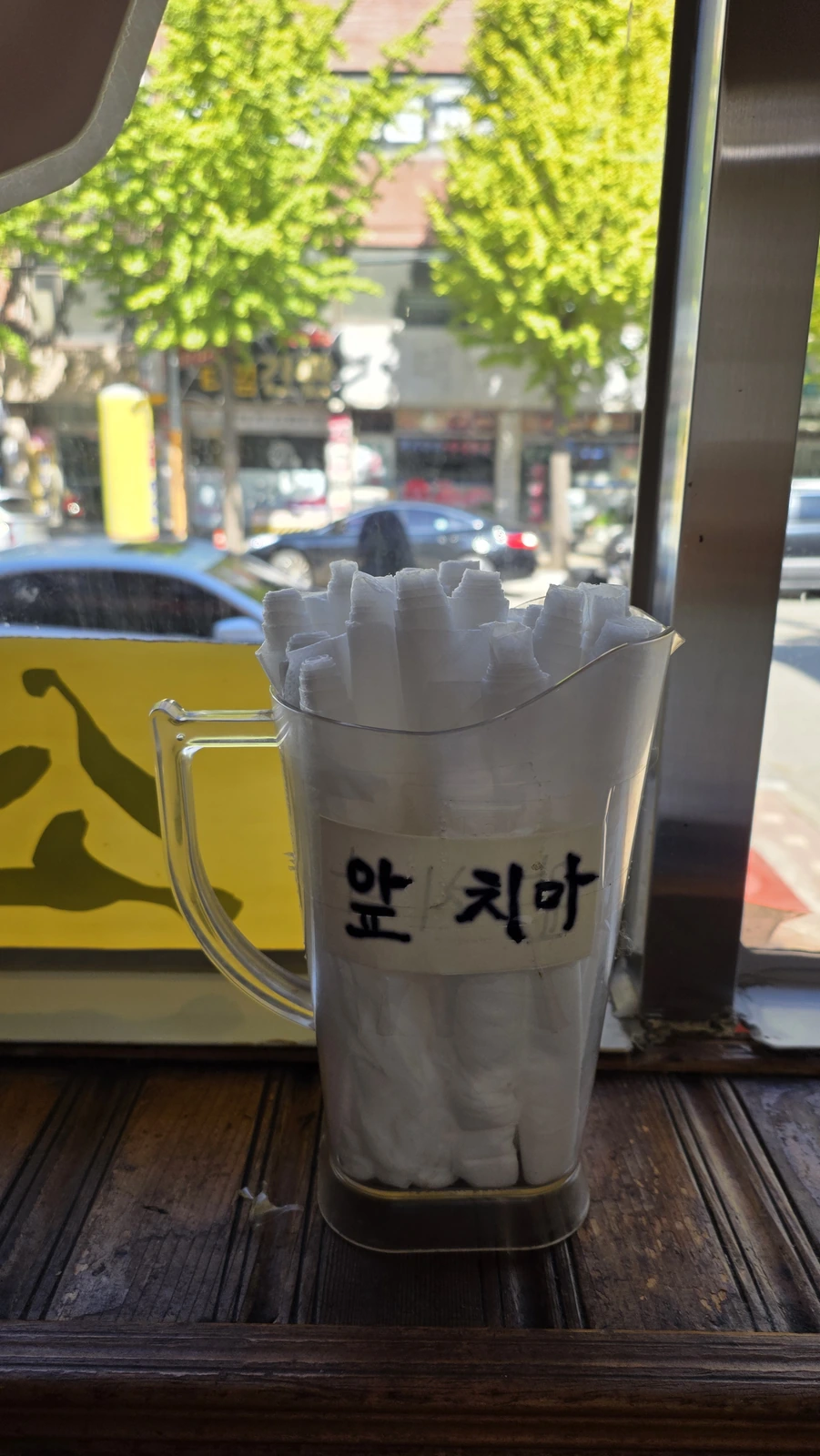 Folded aprons in a container labeled “aprons” by the window