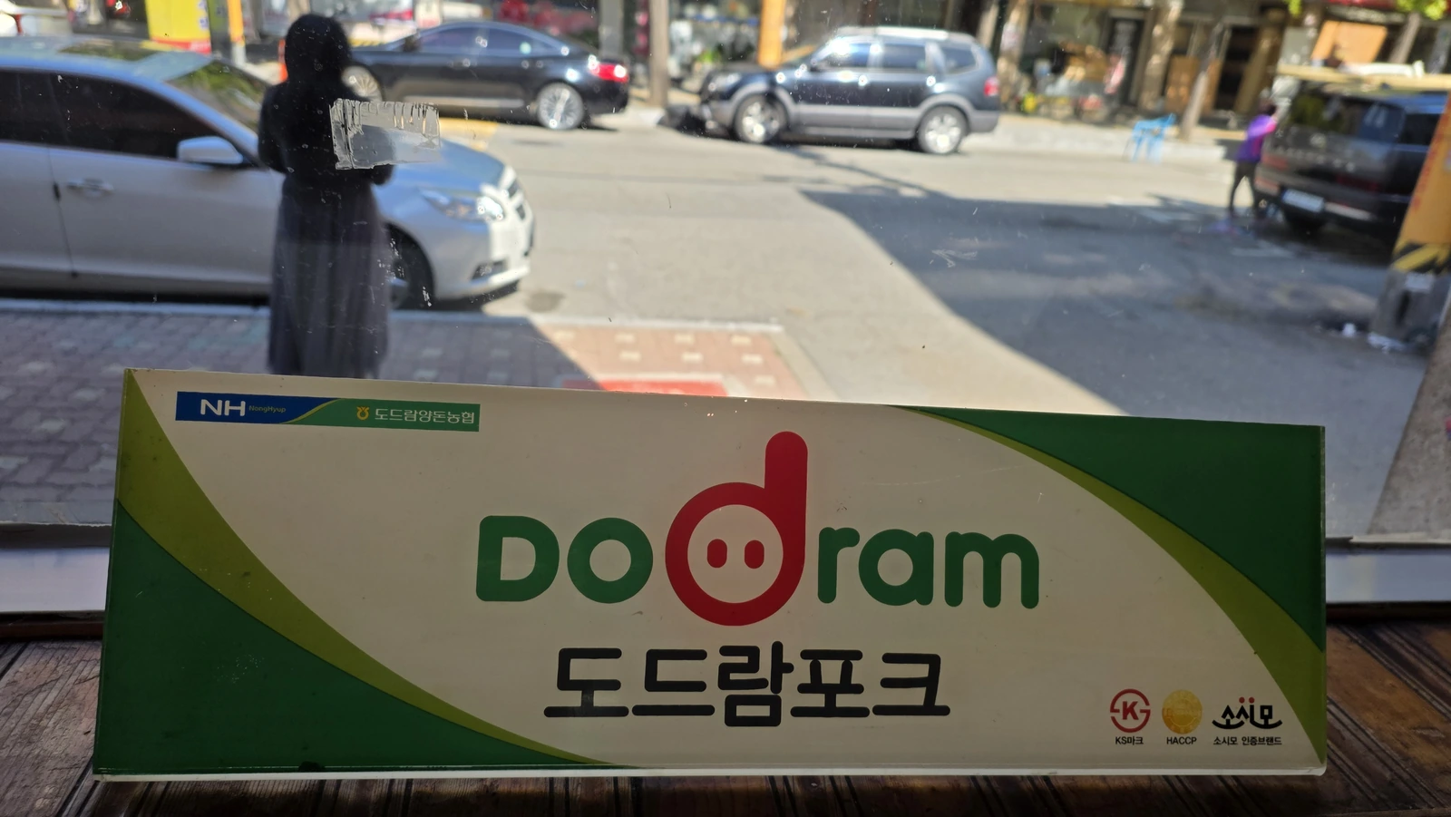 A sign bearing the Dodram Pork logo by the window